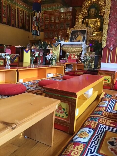 benches with red tops with a big golden budda alter in the background