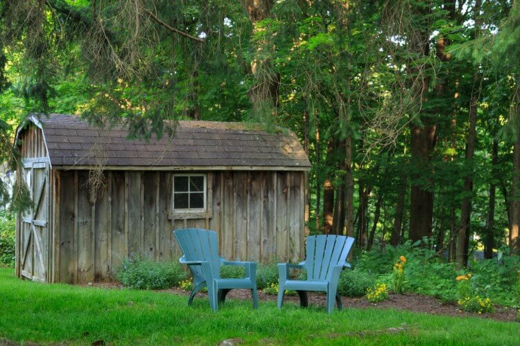 two blue chairs in front of a weathered brown barn 