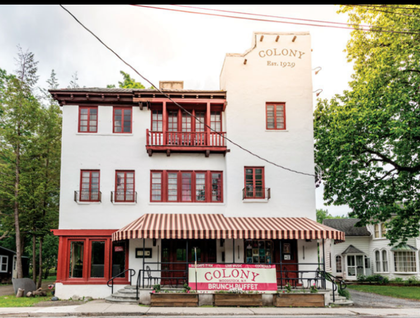 a white building in moraccan style with teh words colony cafe painted on it. 